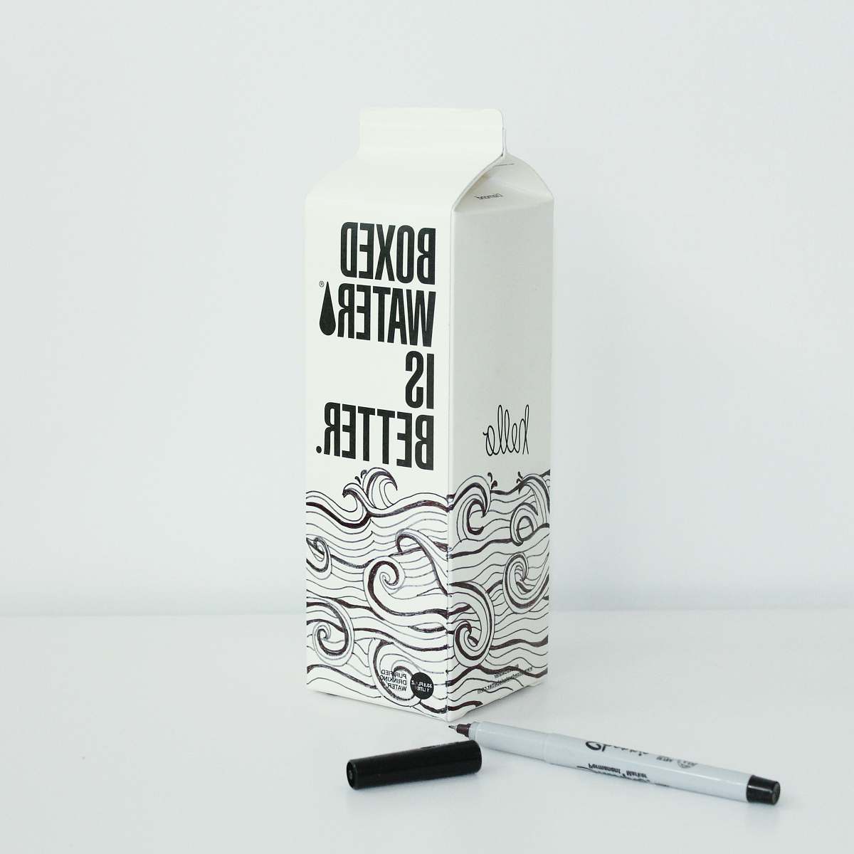 grey Boxed water is Better carton with waves drawn on it with a sharpie 